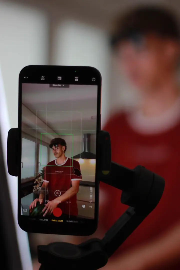 A food creator framing a smartphone video in a kitchen